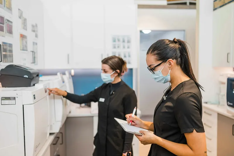 Two clinic staff members using a multifunction printer