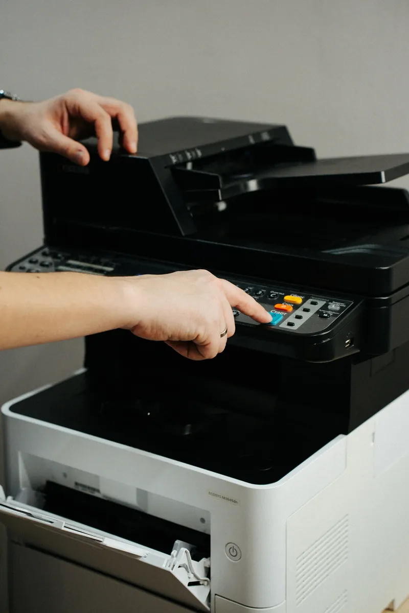 A hand pressing buttons on a laser printer control panel