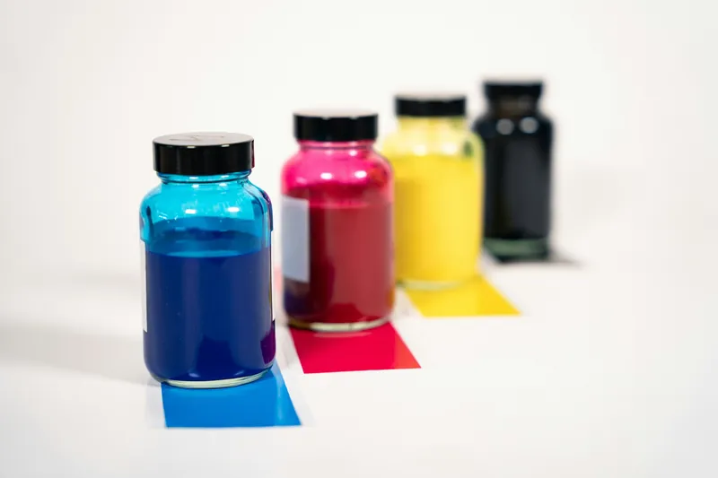 Cyan, magenta, yellow and black refill ink bottles with ink swatches