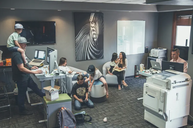 A busy open-plan office with a multifunction copier against the wall